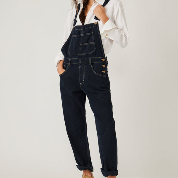 front view of model in overalls. you see the large bib pocket detail, side buttons and tapered legs. shows white contrast seam detail.