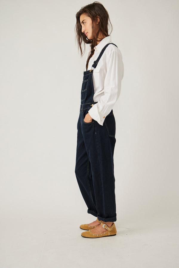 side view of model in overalls. here you can see the tapered legs which the model has rolled to her ankles. as well as a side pocket.