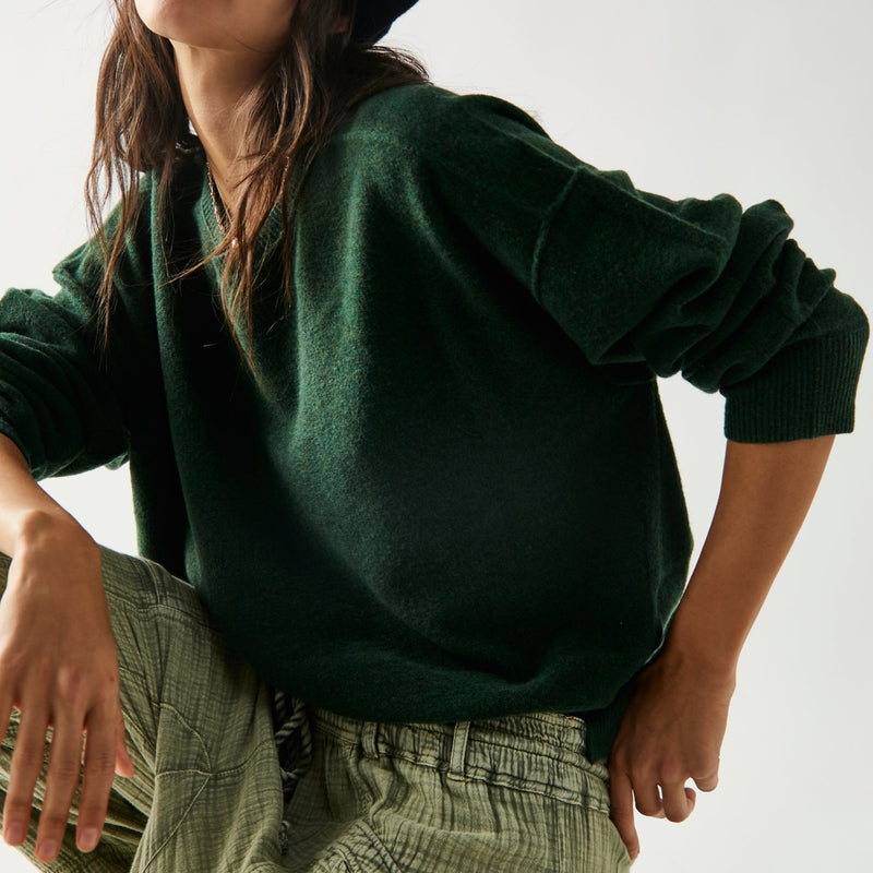 Front/side view of model wearing pullover. Shows the exposed seaming. Also shows the dropped shoulders and ribbed detailing. . 