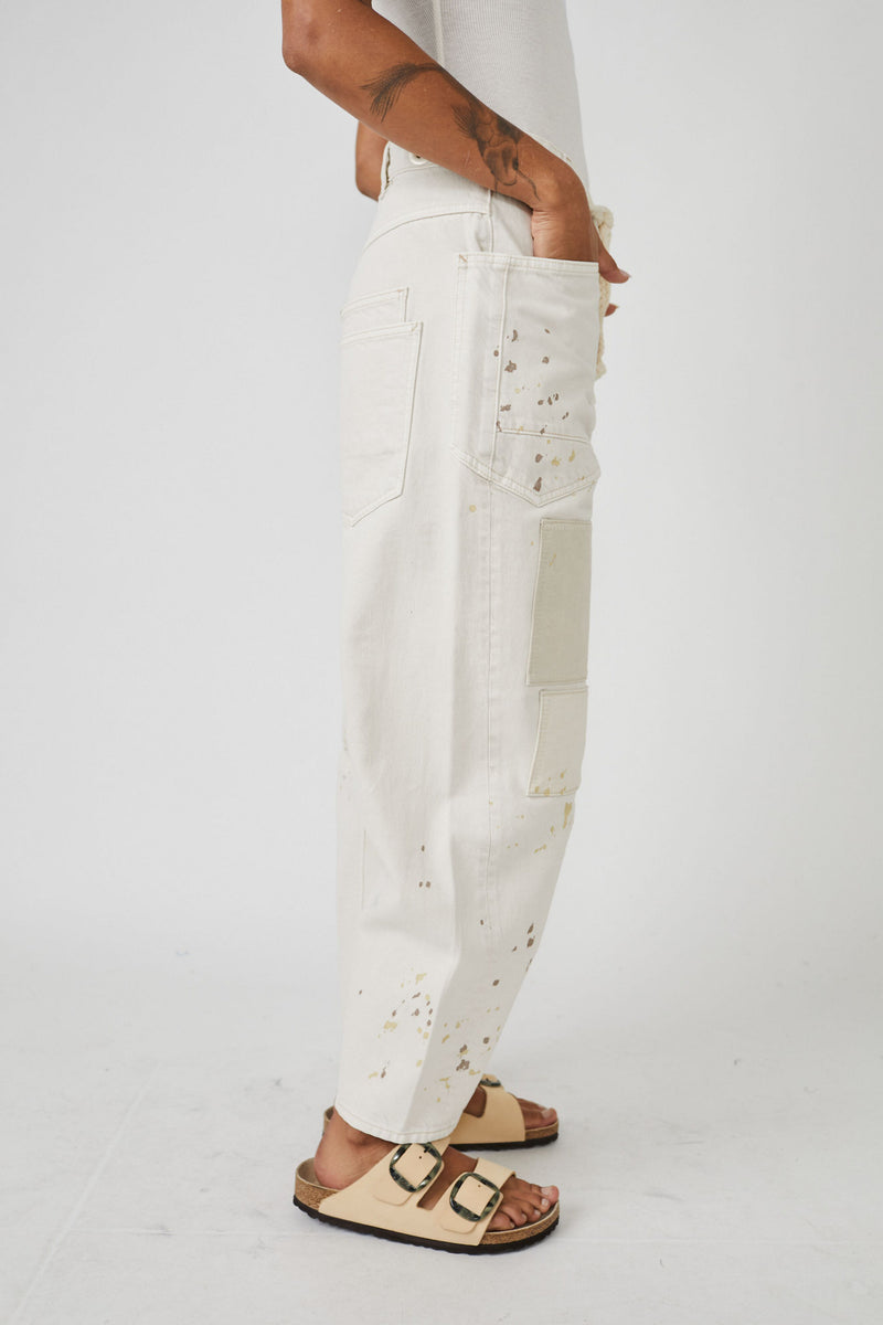 side view of model in pants. shows the models hand in the large pocket, paint splatter and wide legs.
