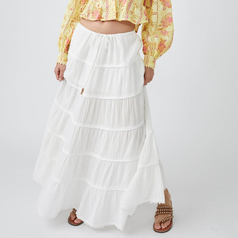 Front view of white, tiered maxi skirt. Mid rise with tie waist. Billowing A-line silhouette 