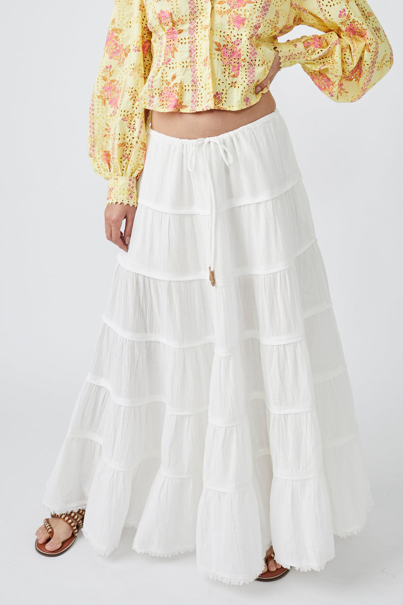 Another image of the front of the skirt. White, tiered maxi skirt. Mid rise with tie waist. Billowing A-line silhouette 
