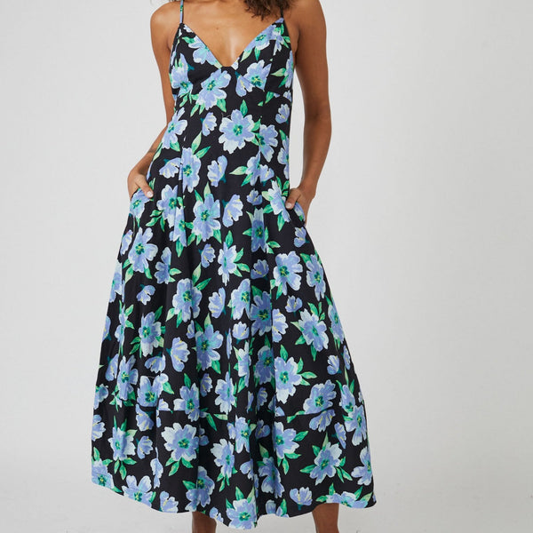 Front view of dress. Midi length, with v-neckline, a-line silhouette, all over blue floral print on top of solid black. Side pockets are showacased.