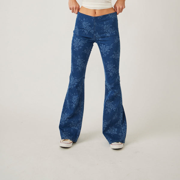 a front view of model in jeans. you can see the mid rise and flare legs. there is a faded white floral print all over.
