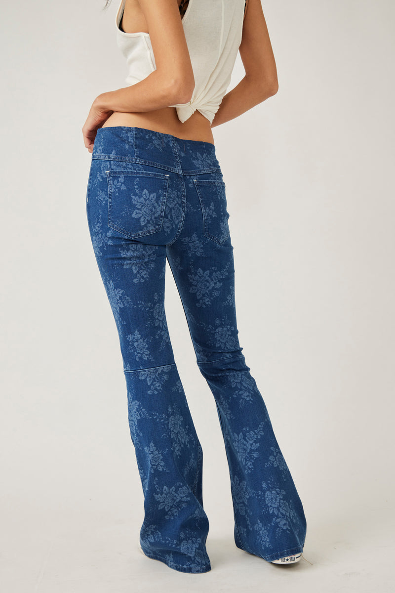 back view of model in jeans. here you can see two back pockets, a seam at the back of the knees, flare legs and an all over floral print.