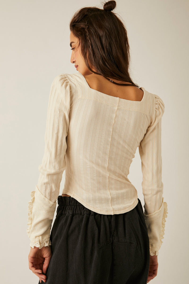 back view of model wearing top. there is a square back, a seam running down the center and the rounded hem is shown.