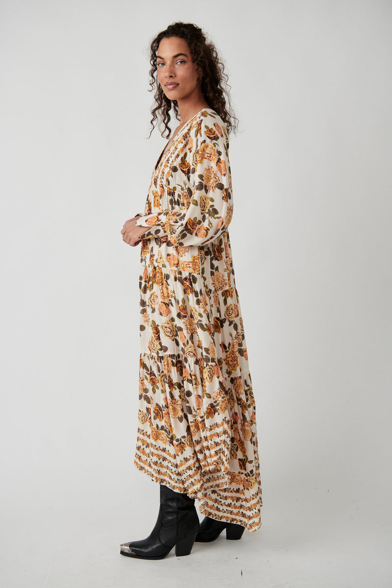 side view of model in dress. shows the flowy tiered skirt with a longer hemline in the back. 