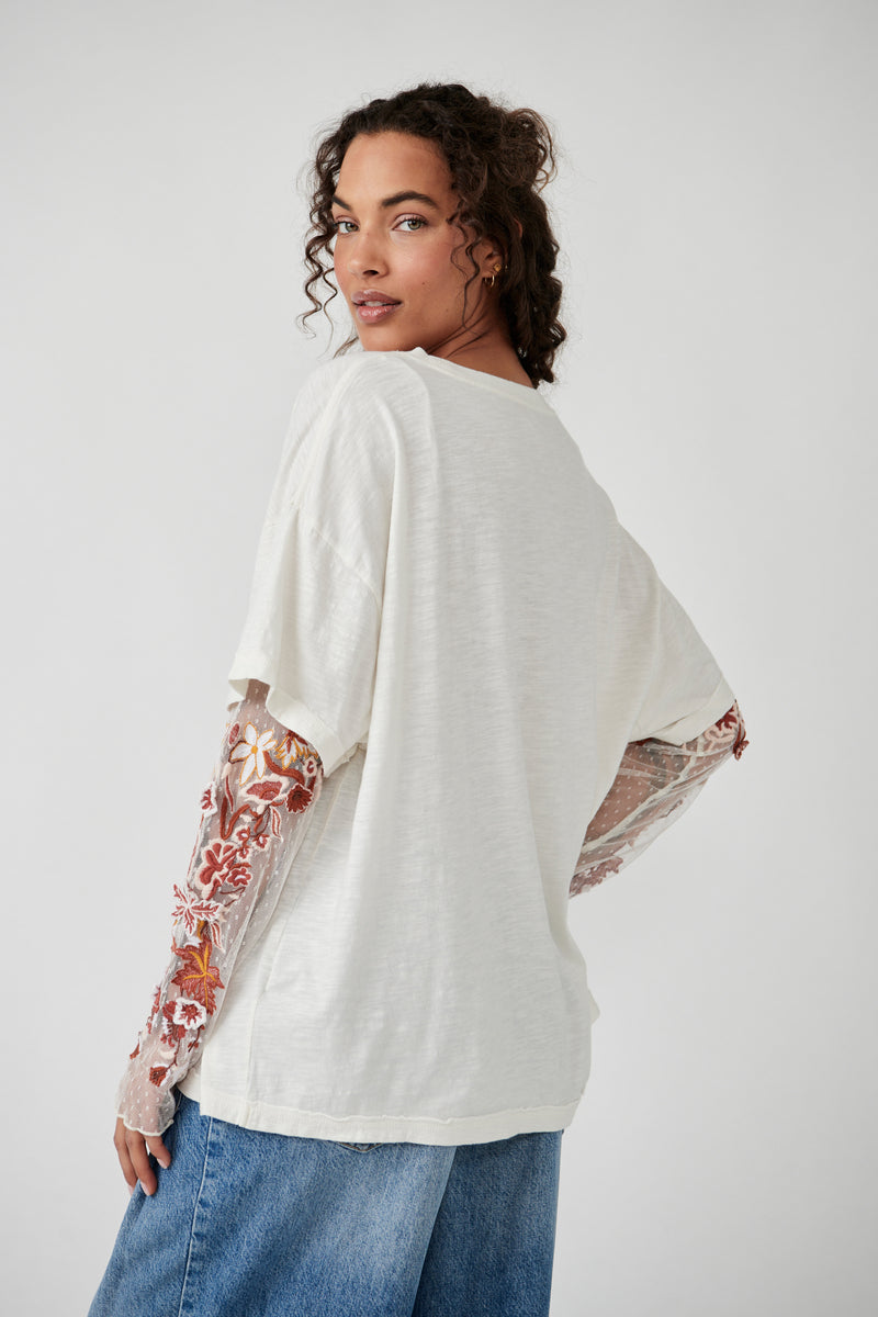 back view of model in shirt. shows oversized fit, sheer embroidered sleeves and longer length.