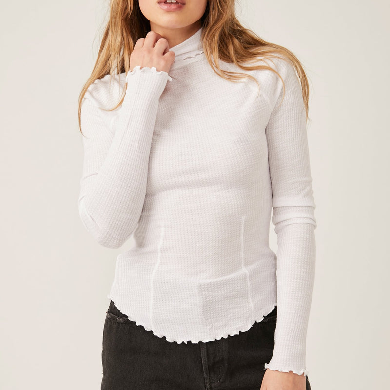 Front view of model wearing top. Shows the turtleneck neckline. Also shows the lettuce trim on the cuffs and the defined seaming.  Edit alt text