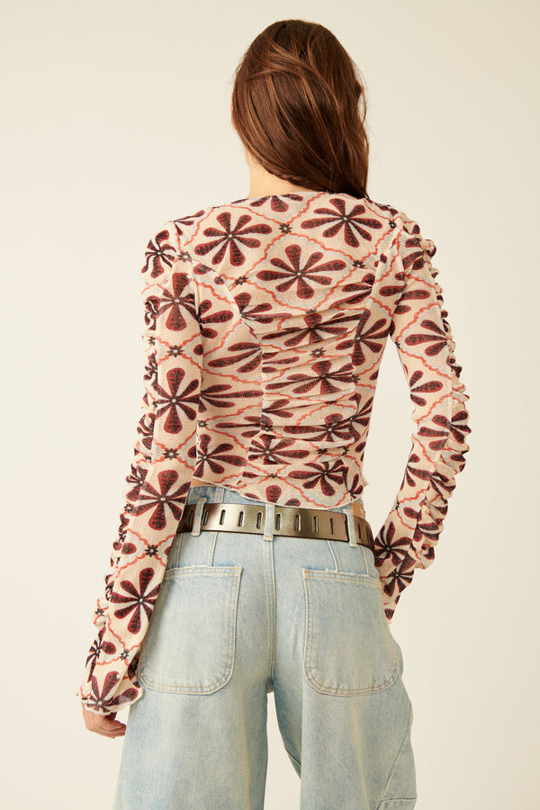 back view of model wearing the through the meadow top. shows the flutter sleeves. also shows the fitted, cropped silhouette of the top, and the lettuce trim hem.