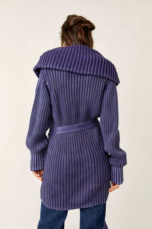 back view of the model wearing the ryanne long haul cardigan in navy. shows the oversized sleeves. also shows the shawl neckline, the belt and ribbed detailing.. 