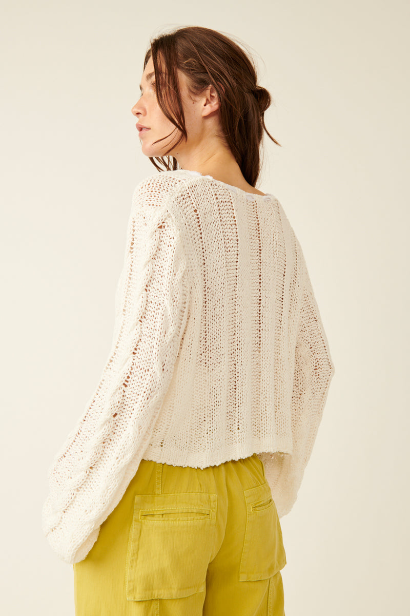 back/side view of the model wearing the robyn cardi. shows the back is little longer the front. shows the cropped length, and the exaggerated sleeves.  