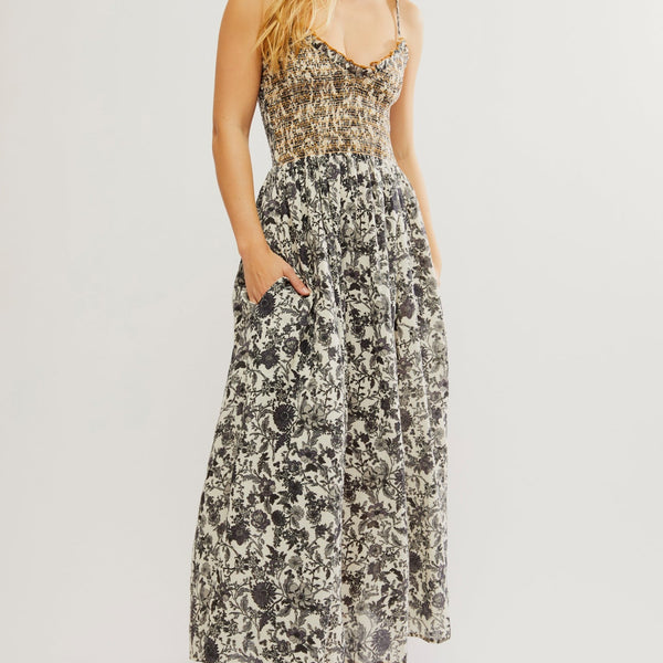 front view of the model wearing the sweet nothings midi dress. shows the smocked bodice. also shows the slight v neckline, the side pockets and the floral print throughout. 
