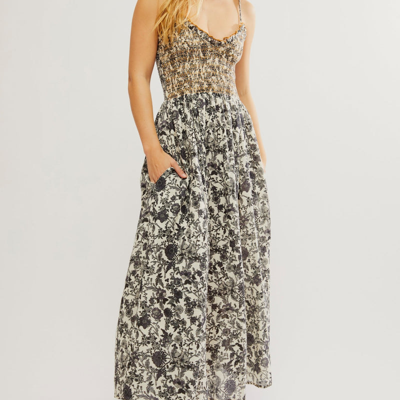 front view of the model wearing the sweet nothings midi dress. shows the smocked bodice. also shows the slight v neckline, the side pockets and the floral print throughout. 