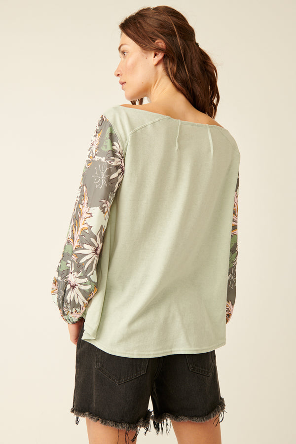 back view of model wearing the picking petals top. shows the billowy silhouette. also shows the floral print sleeves.