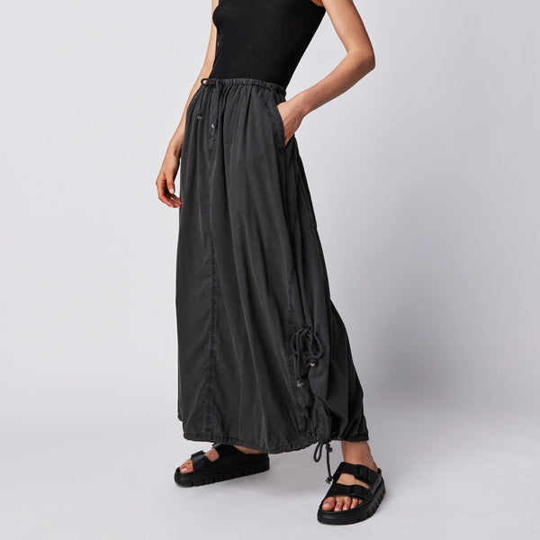 front view of the model wearing the picture perfect parachute skirt. shows the elastic, drawstring waist. also shows the drawstring feature at bottom curve hem, the dropped side pockets and the slouchy fit. 