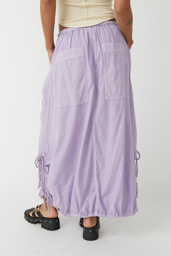 back view of the model wearing the picture perfect parachute skirt. shows the back big patch pockets. the elastic drawstring waist and the drawstring feature on the side of the curved hems. 