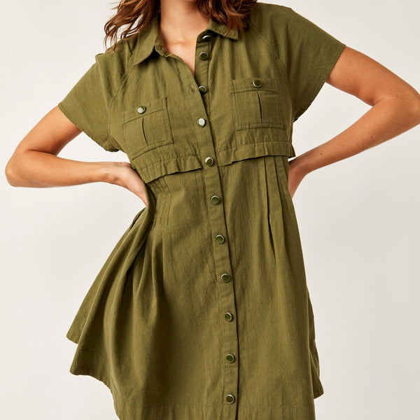front view of the model wearing the ronnie poplin mini dress. shows the button down closure. also shows the two front pockets, the front pleating and traditional collar. 