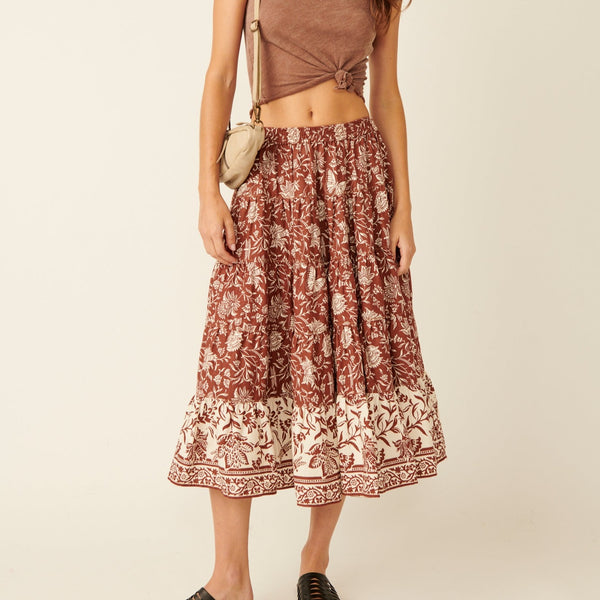 front view of the model wearing the full swing printed midi skirt. shows the low waist. also shows the a line hem, the tiered look, and the stretchy waistband.  