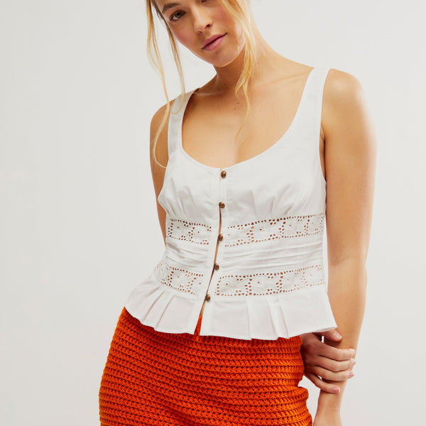 front view of the model wearing the kianna lack tank. shows the open lace through the mid section. also shows the ruffle at the bottom, the front button closure, the low scoop neckline. 