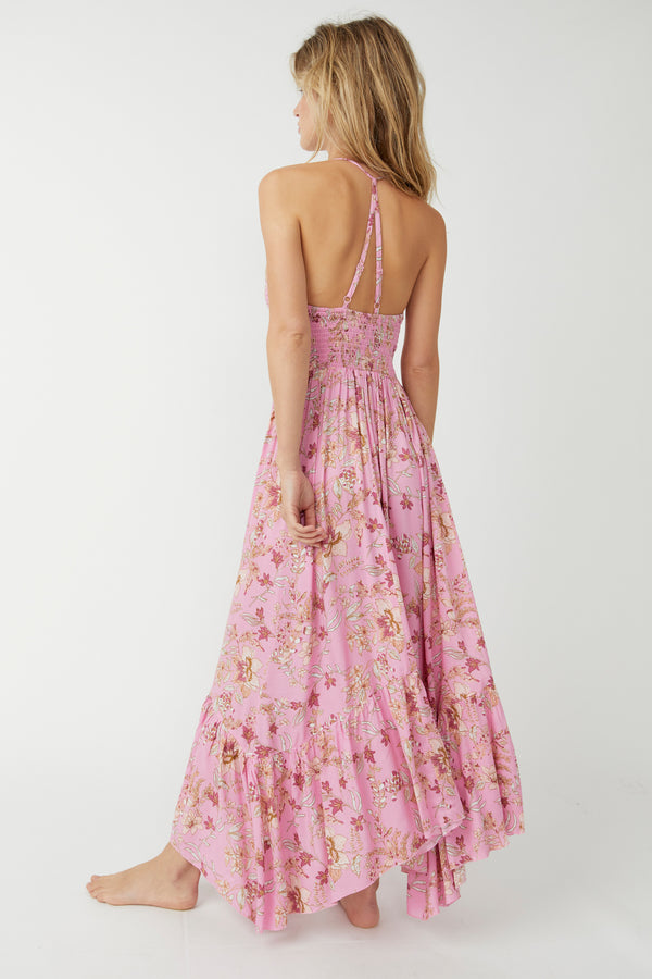 back view of the model wearing the heat wave printed maxi. shows the criss cross adjustable straps. also shows the asymmetrical hemline and the smocked bodice. 