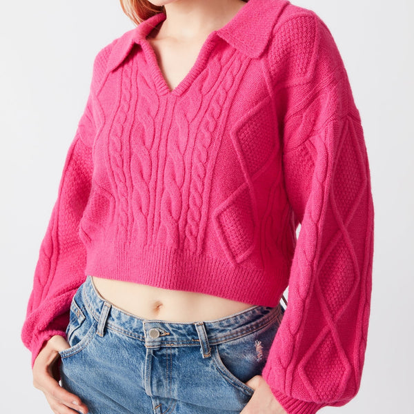 Front view of model wearing sweater. Shows the collared v neck. Also shows the cable knit detail, the balloon sleeves and the pullover style. 