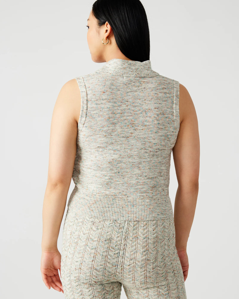back view of the model wearing the amina sweater. shows that the sweater is sleeveless. also shows the collared neckline and the cropped length. 