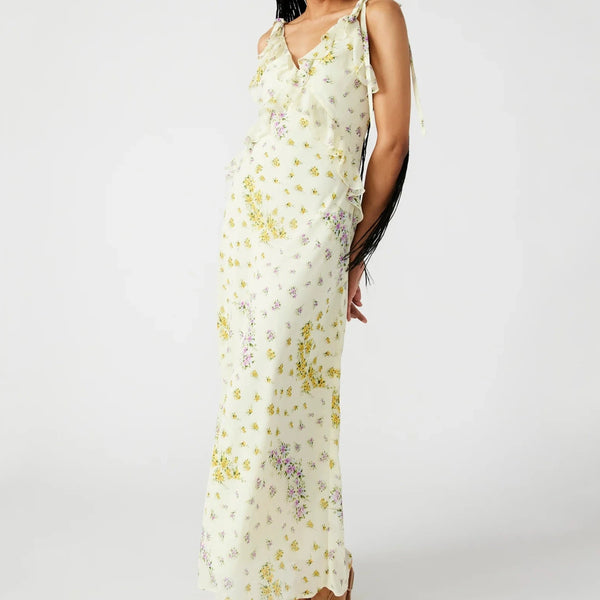 front view of the model wearing the adaline dress. shows the adjustable straps with ties. also shows the front and back ruffles, the v neckline and the floral print. 