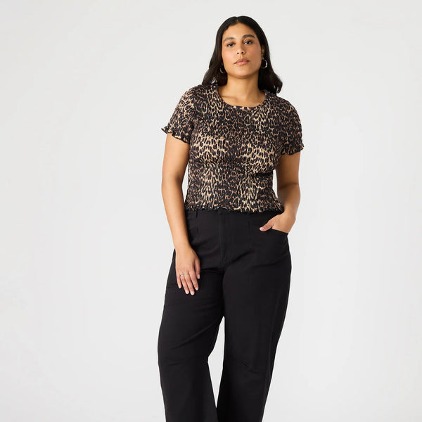 front view of the model wearing the fia top. shows the cheetah print. also shows the smocking throughout, the lettuce trim on the hemlines and the short sleeve. 