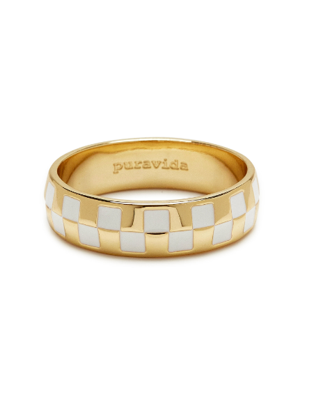 Another picture of the gold and white checkered ring on a flat surface.