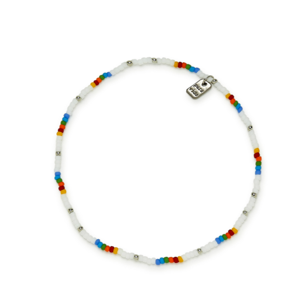 Anklet is on a flat surface. Shows multi colored beads. Has a mini rectangular charm with "pura vida" in center.