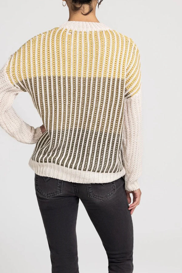 Person wearing a patterned sweater with yellow and white colors on a plain background