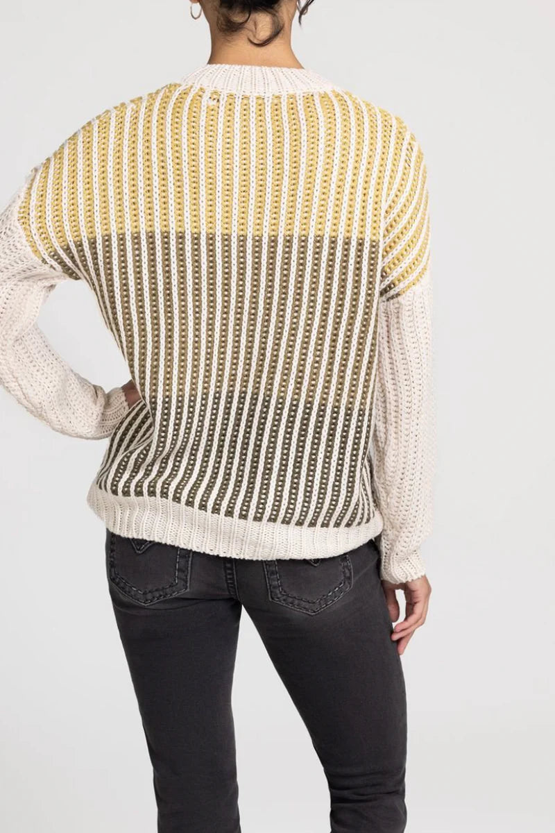 Person wearing a patterned sweater with yellow and white colors on a plain background