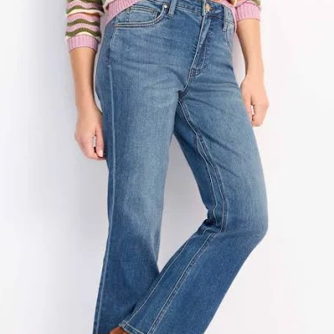 Person wearing a colorful striped sweater and blue jeans on a white background