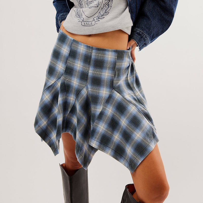 front view of model wearing XIA plaid mini skirt in navy combo. shows the mid rise. also shows the asymmetrical pleating, the a-line shape. 