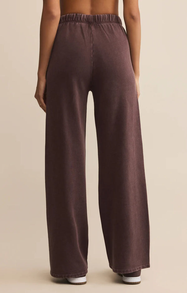 Brown wide-leg pants worn by a person on a beige background