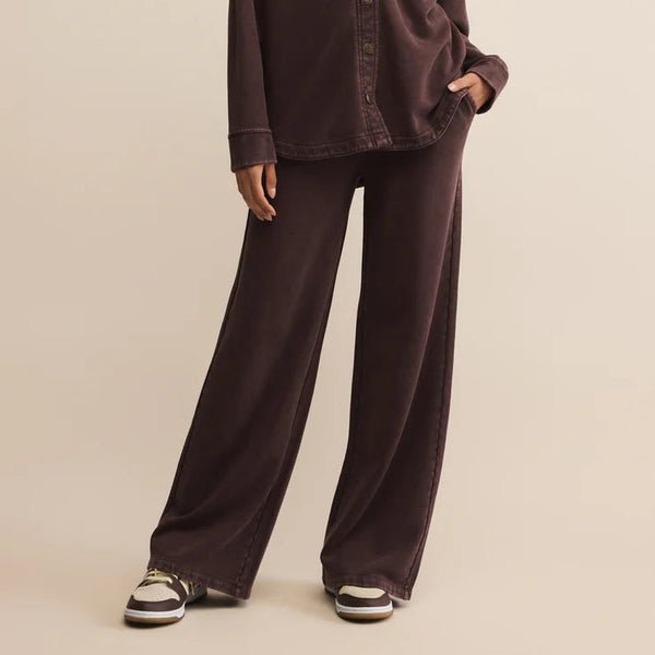 Woman wearing a brown shirt and pants on a beige background