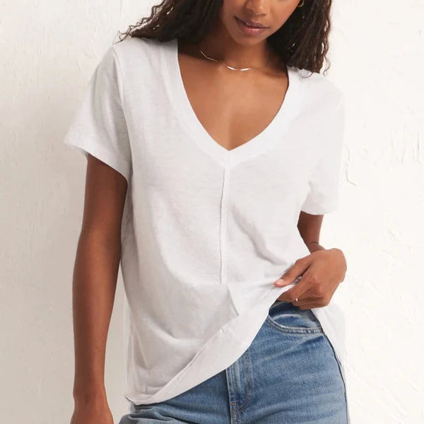 front view of the model wearing the asher v neck tee in white. shows the v neckline. also shows the relaxed fit and the front middle raw hem down the middle. 