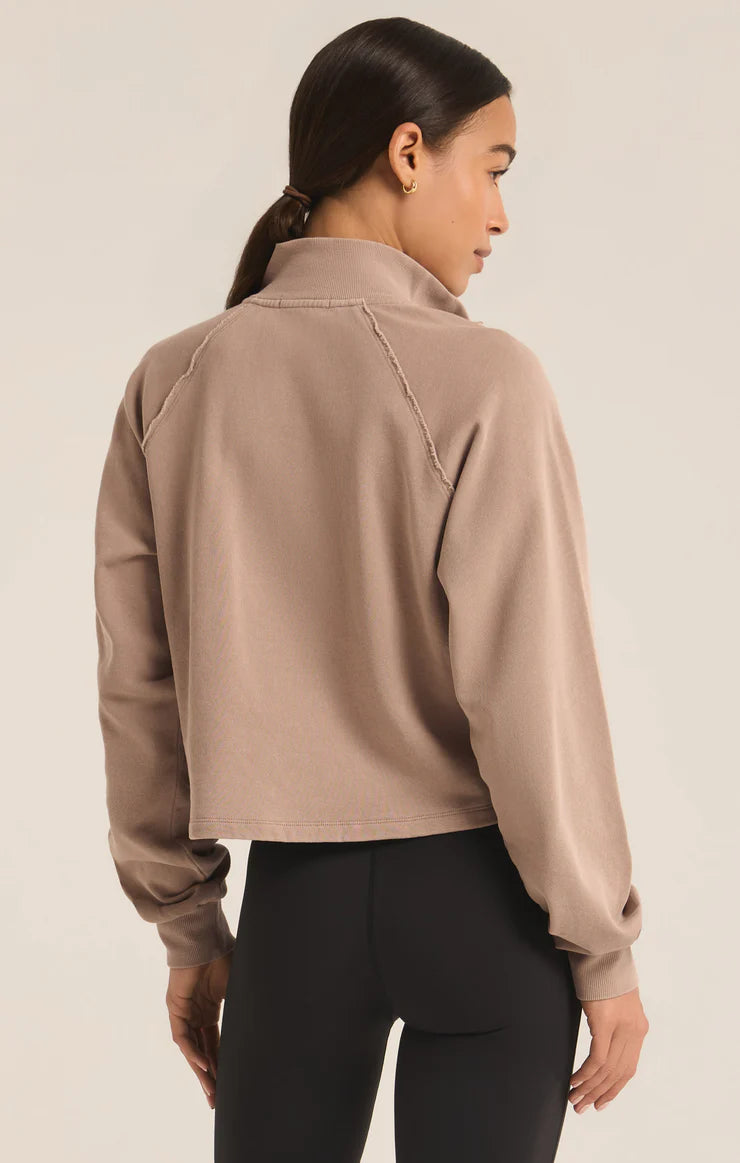 back view of the model wearing the on the run half zip sweatshirt. shows the exposed seams. also shows the cropped length, the regular fit and the collar. 