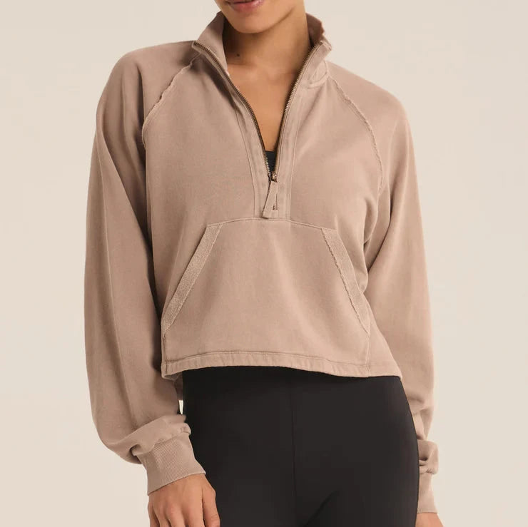 front view of the model wearing the on the run half zip sweatshirt. shows the quarter zip. also shows the pouch pocket, the regular fit, cropped length and exposed seams. 