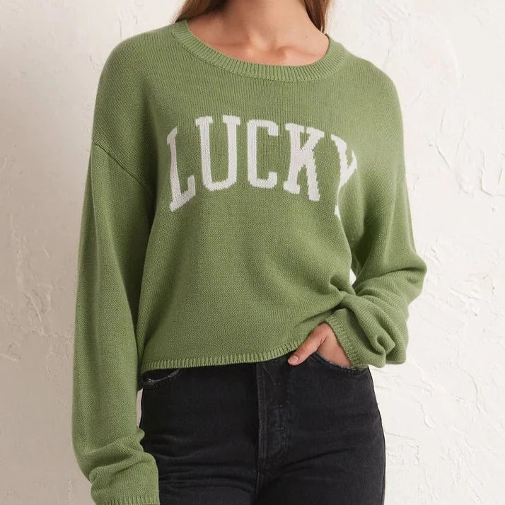 front view of the model wearing cooper lucky sweater. shows the LUCKY intarsia at front. also shows that the sweater sits at waistline, also shows the drop shoulders and the crew neckline. 
