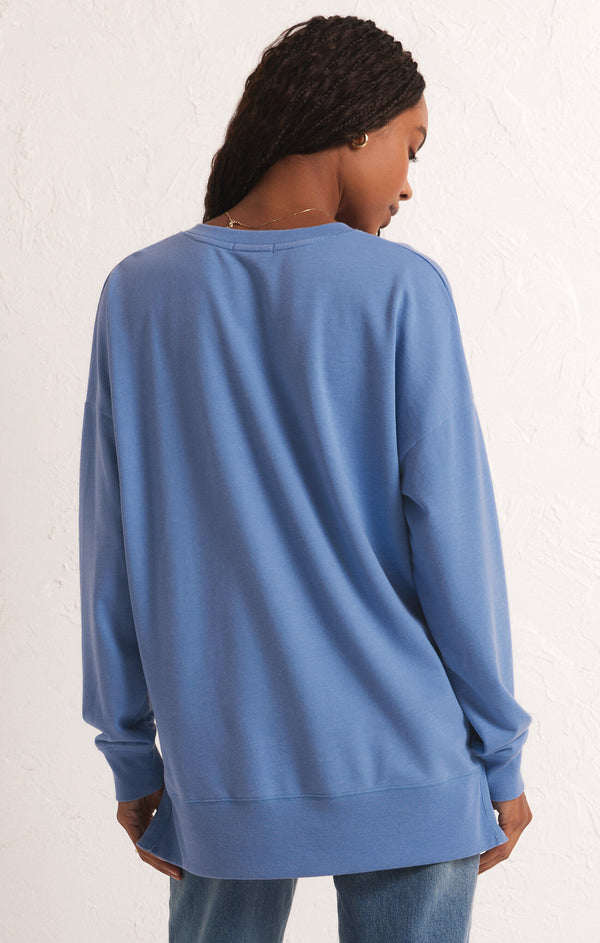 back view of the model wearing the modern v neck weekender. shows the ribbed detailing. also shows the oversized fit, the side slits and the dropped shoulders. 