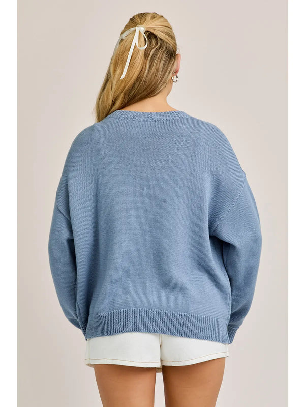 back view of the model wearing the horseshoe cardigan. shows the ribbed detailing. also shows the light blue color, the dropped shoulders and the slight oversized fit. 