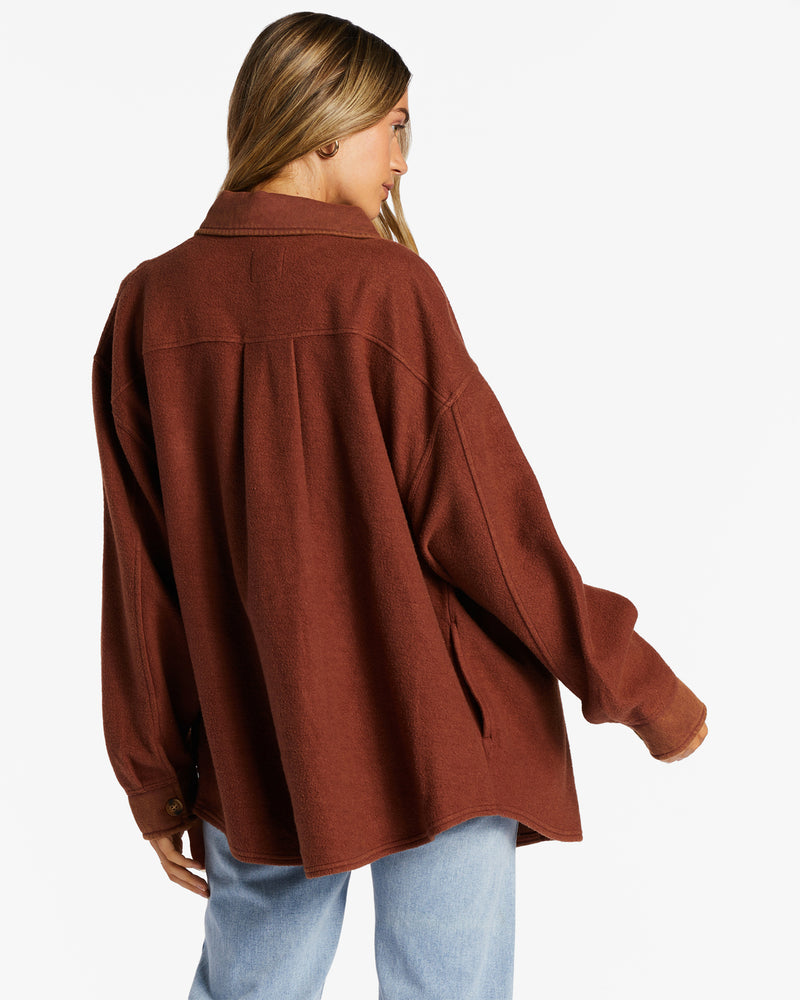 back view of model in shacket. shows the dropped shoulders, oversized fit, visible seams running across the back and down the sleeves.