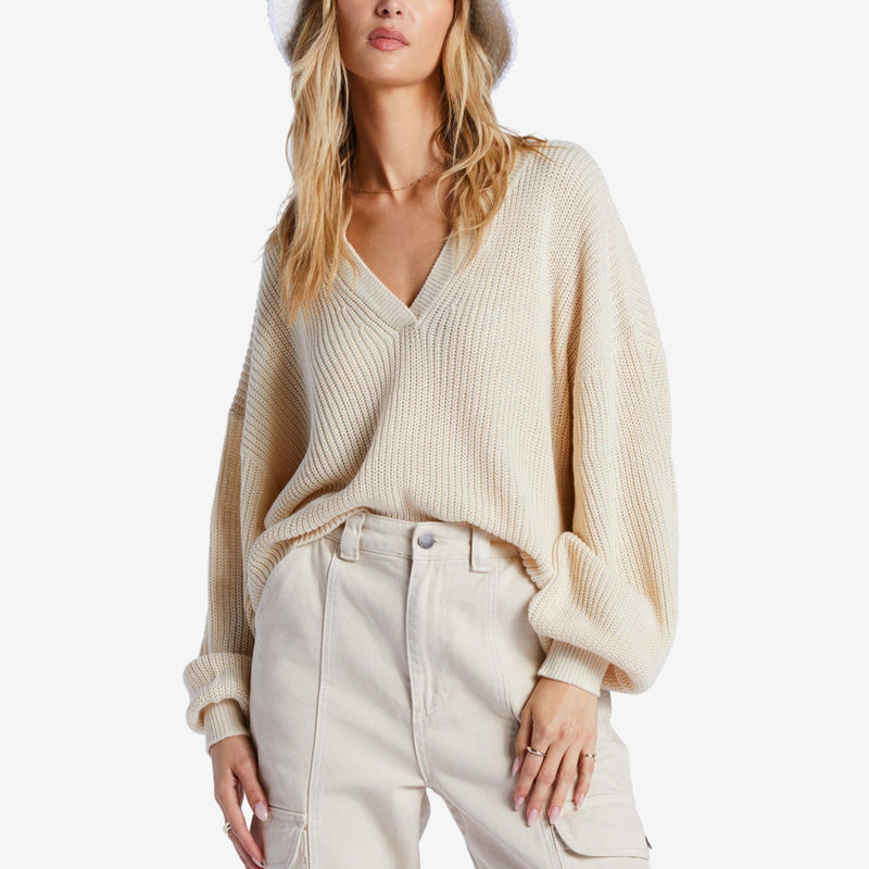 front view of model in sweater. shows the low v-neckline, relaxed silhouette, and long blouson sleeves. dropped shoulders are also visible.