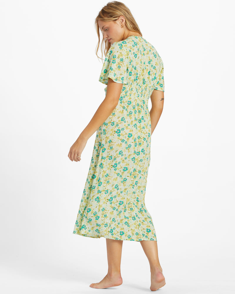 back view of the model wearing the your girl dress. shows the back smocking waist. also shows the short flutter sleeves, and the midi length