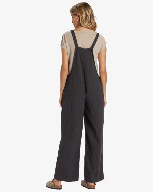 back view of the model wearing the pacific time romper/jumpsuit. shows the back straps. also shows the relaxed fit. 
