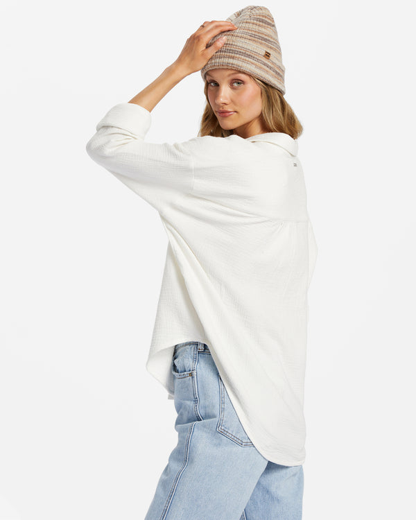 shows side view of model in shirt. here you can see the dropped shoulders, oversized fit, and curved hem.