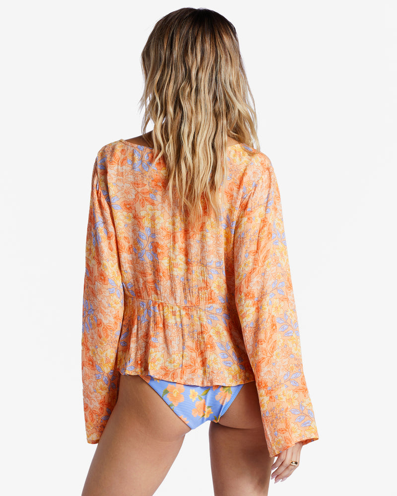 shows back view of model in blouse. shows the flowy fit and bell sleeves.