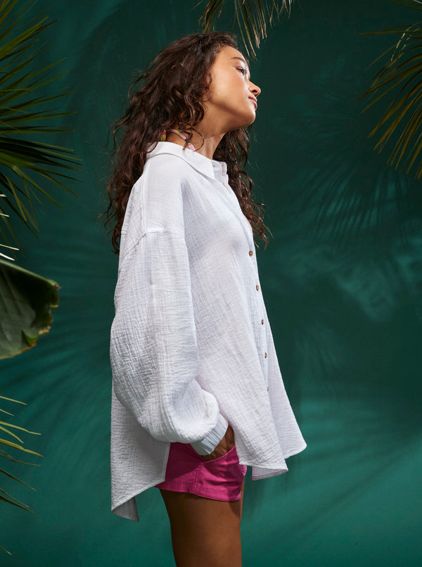 Side view of shirt. Shows the dropped shoulders, Hi-low hemline, and elastic cuffs.